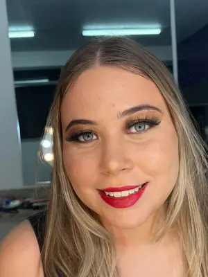 Mulher loira usando maquiagem ousada com batom vermelho e olhos marcados.