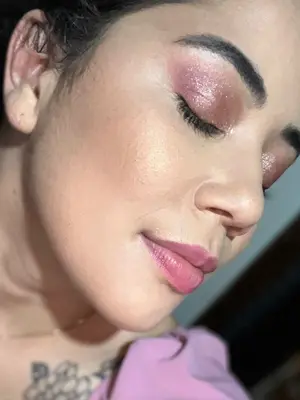 Mulher de perfil usando maquiagem com sombra rosa brilhante.
