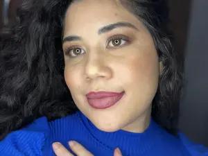 Mulher sorrindo levemente com maquiagem suave e olhar acolhedor.
