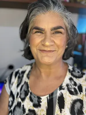 Mulher de cabelos grisalhos usando maquiagem sutil e discreta.