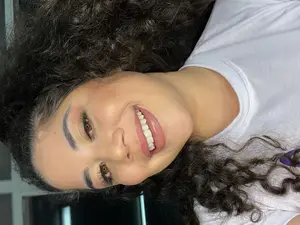 Mulher sorrindo de lado com expressão confiante e beleza autêntica.