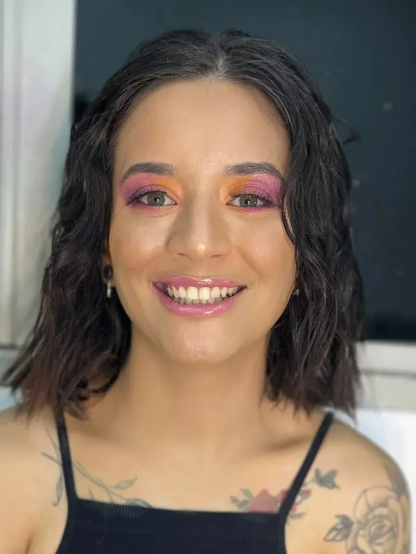 Mulher usando maquiagem artística e colorida nos olhos com glitter.